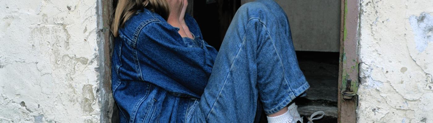 a young girl with head in hands sat on a step