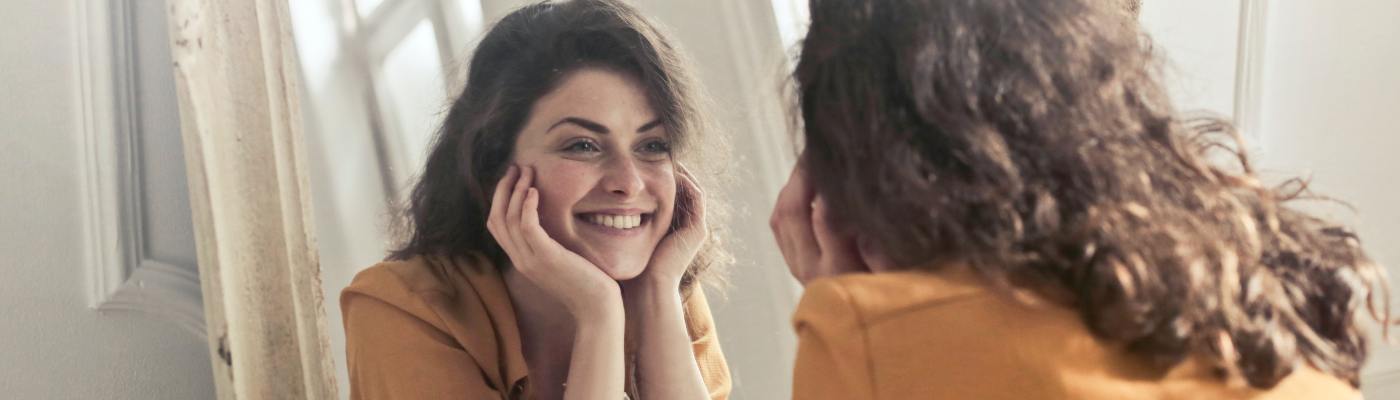 woman looking at herself in the mirror and smiling